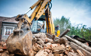 Contractor surveying a cleared demolition site with remaining concrete foundation slabs